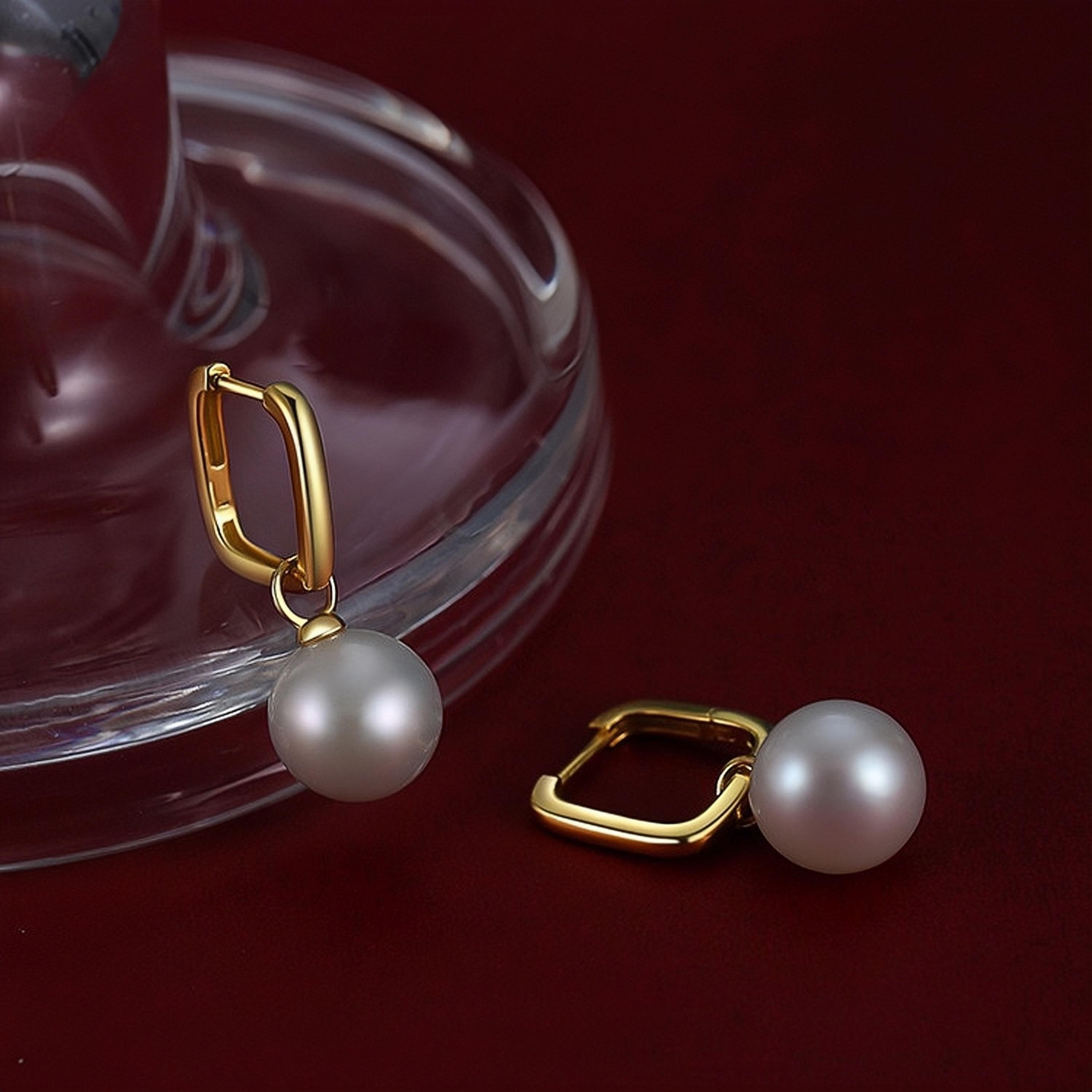 Pearl drop hoop earrings with 10-11mm freshwater pearls and gold-tone hoops styled on deep red velvet for a timeless elegant look.
