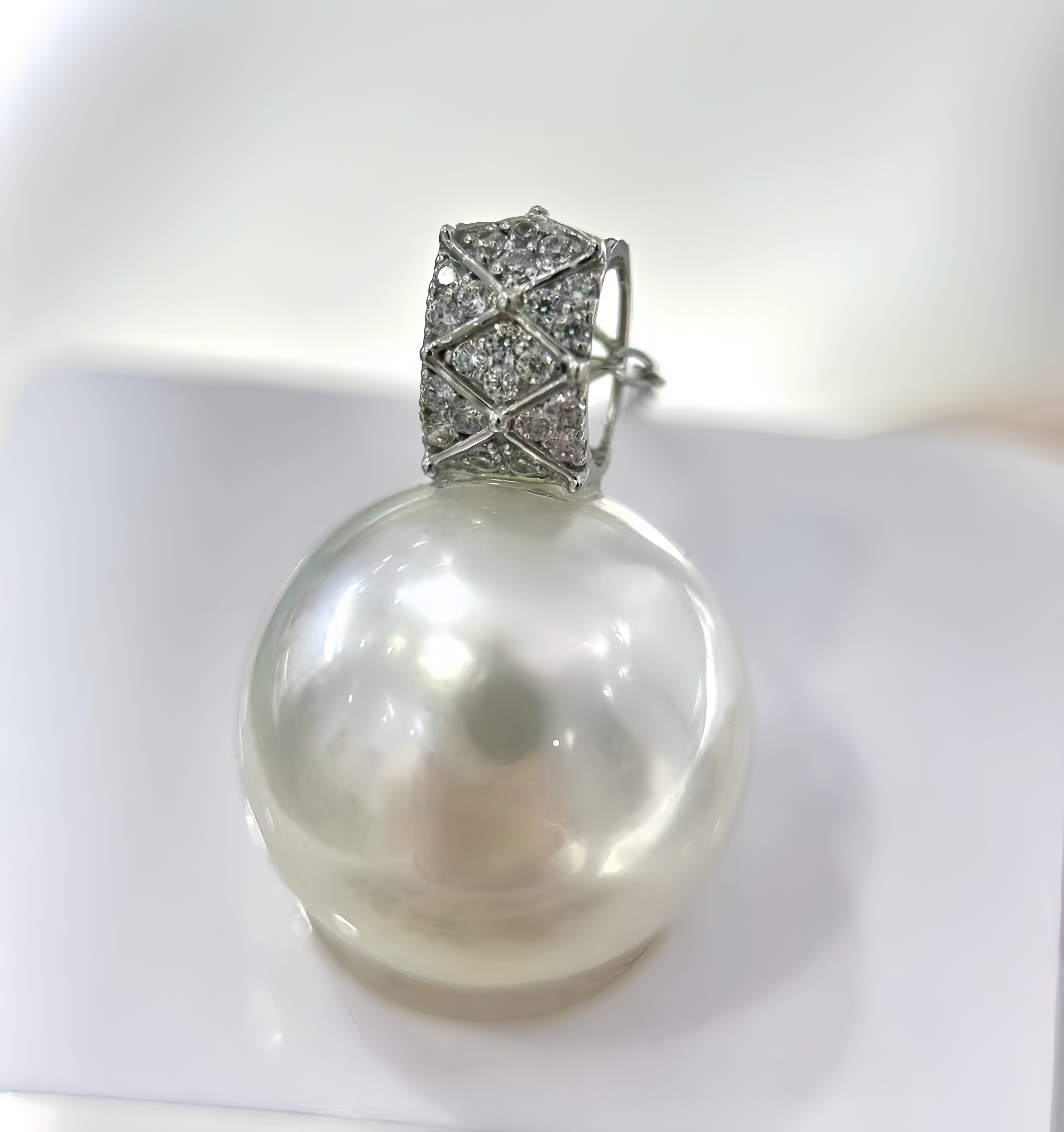 A white freshwater pearl pendant with a silver-toned pavé diamond bail, displayed on a clean white surface.